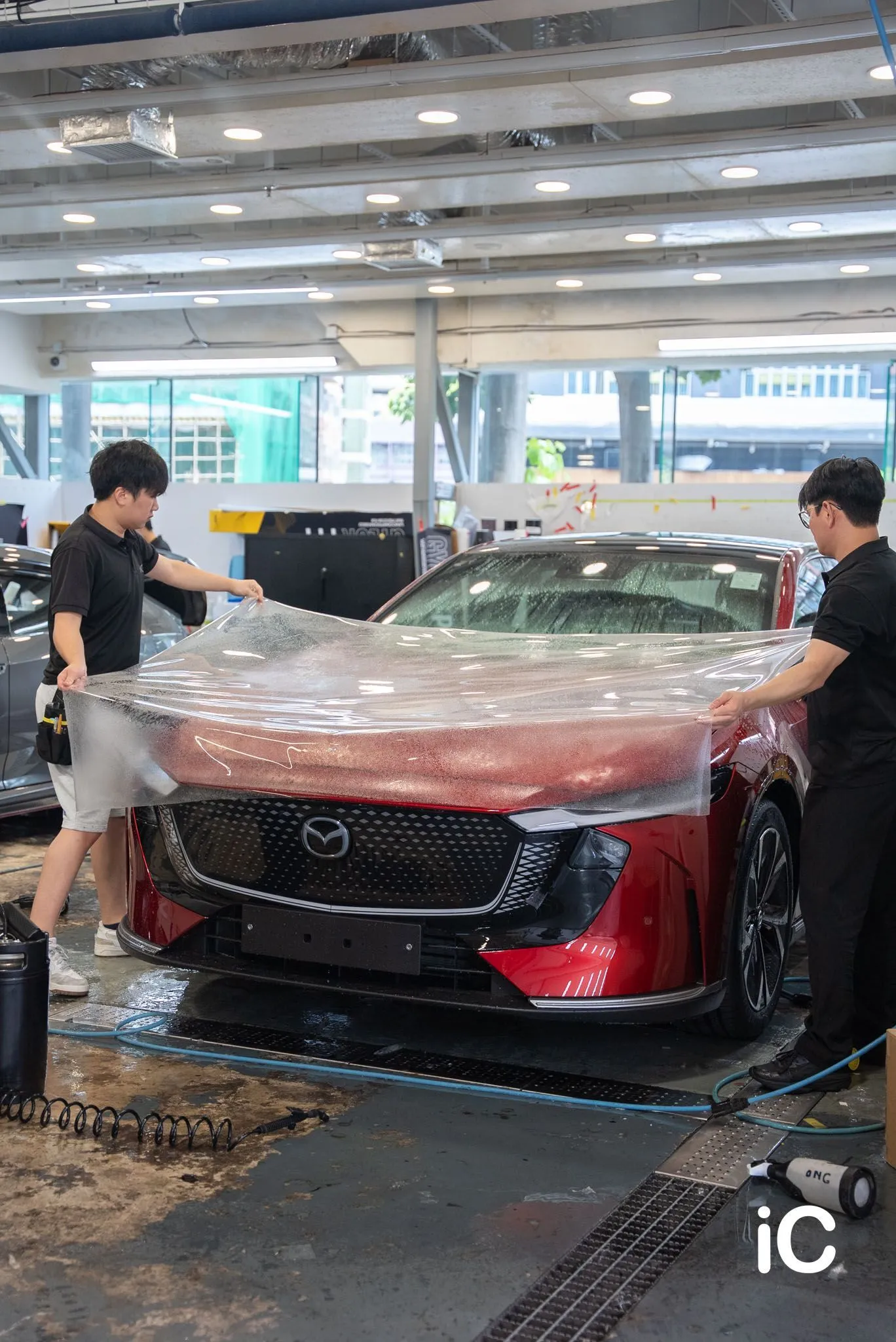 兩位同事將透明 PPF 鋪在 Mazda 6e 頭冚上