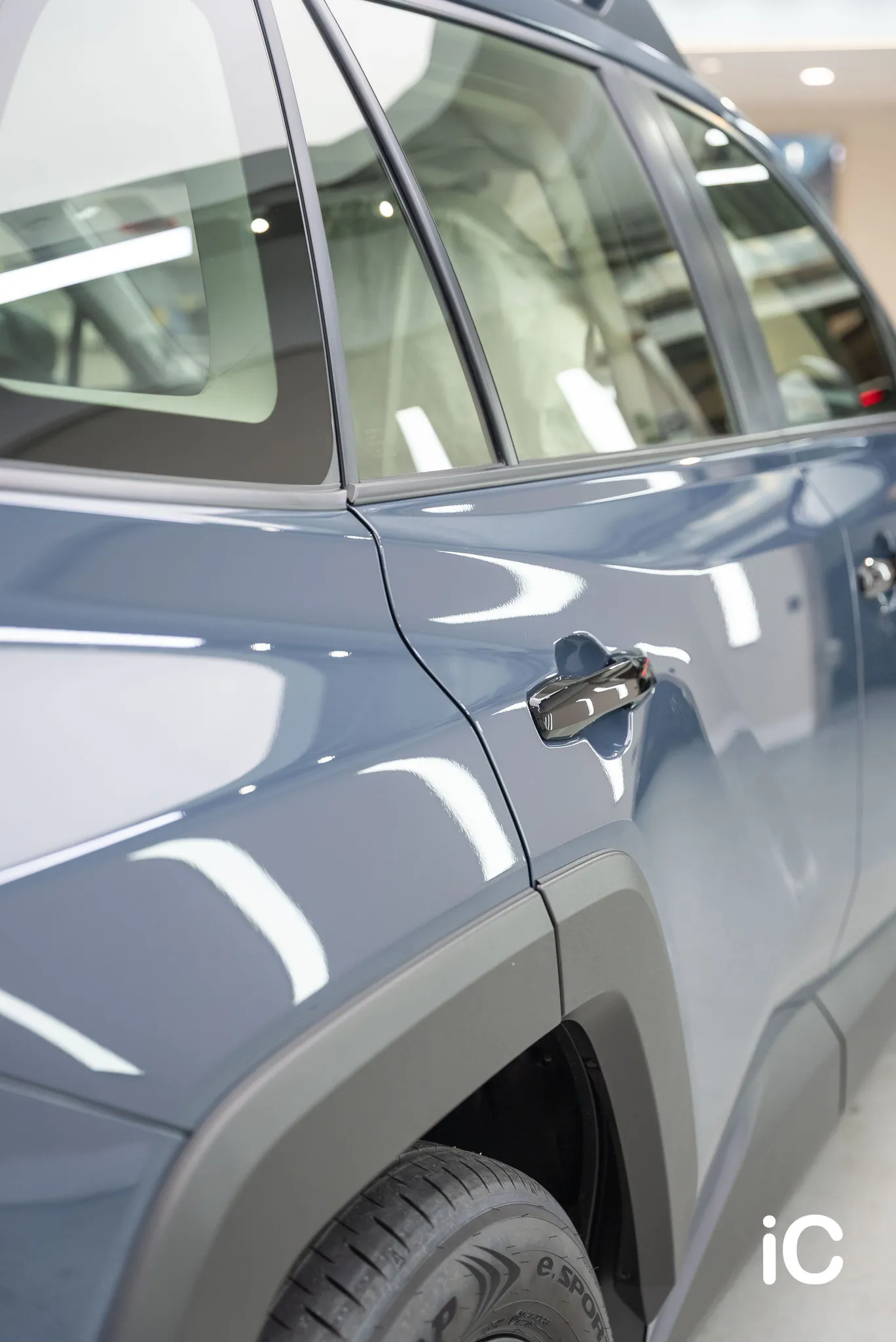 沿 RAV4 後車門向前看的直幅近照，展示車漆反射與光面門柄